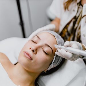 Beautiful young woman having a micro-needling collagen facial beauty treatment in the beauty clinic